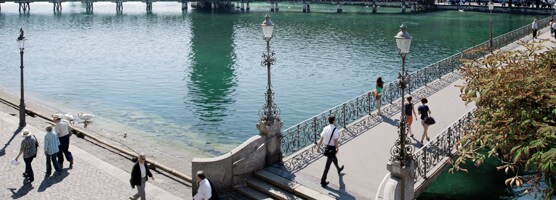 A overview of a lake and people walking on the side walk and the connecting bridge